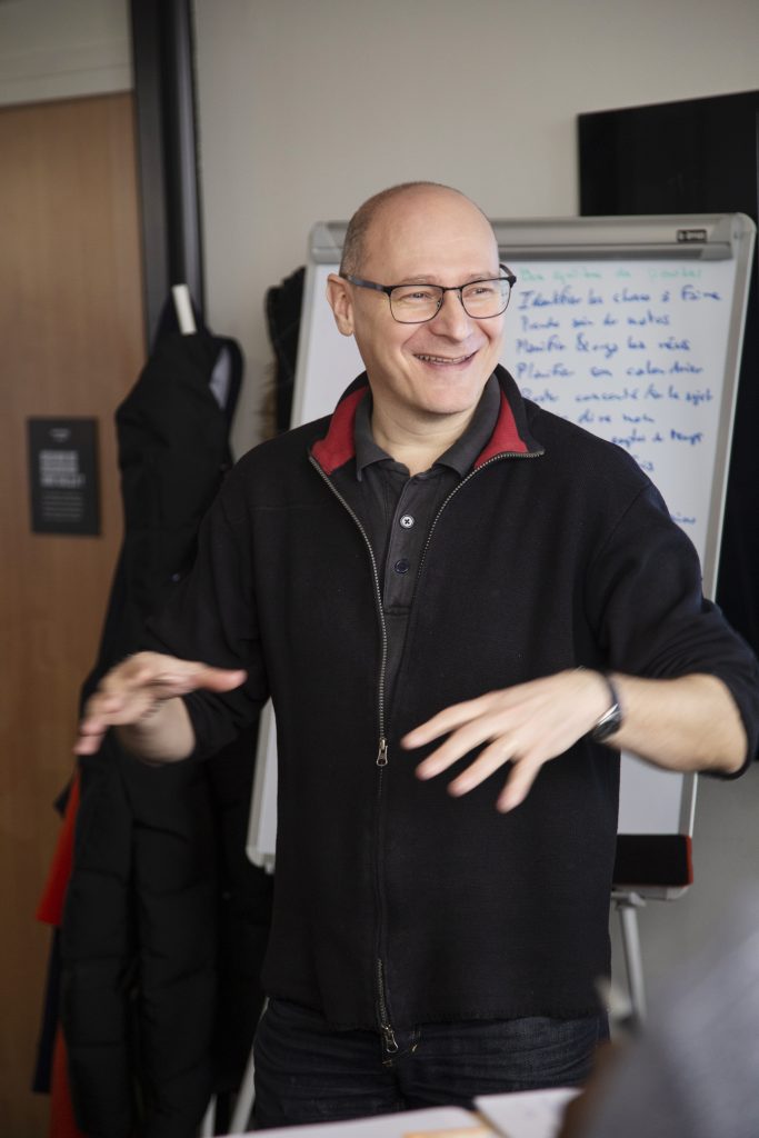 Romain Bisseret, souriant, explique en formation devant un paperboard